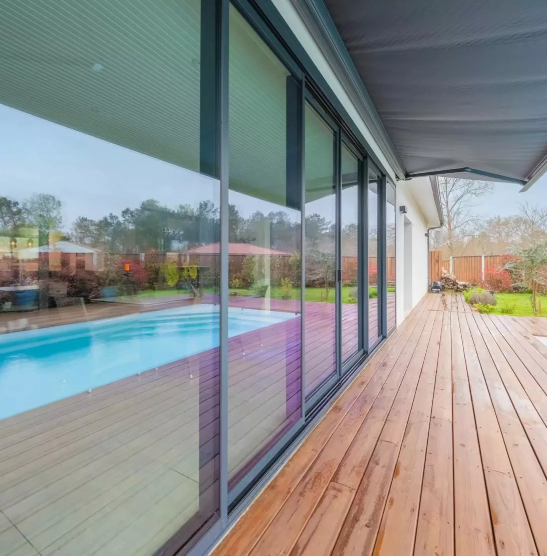 Baie vitrée coulissante sur terrasse bois avec piscine